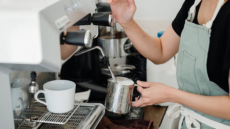 zu sehen ist eine Hand, die gerade Milch an einer Kaffeemaschine aufschäumt- Barista Basic Schulung in Dresden