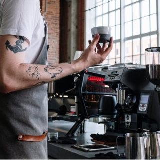 Ansicht eines Mannes neben einer Siebträgermaschine- Barista Kurs mit eigener Maschine und Mühle