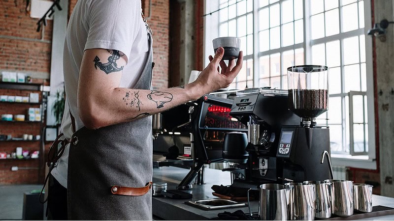 Ansicht eines Mannes neben einer Siebträgermaschine- Barista Kurs mit eigener Maschine und Mühle