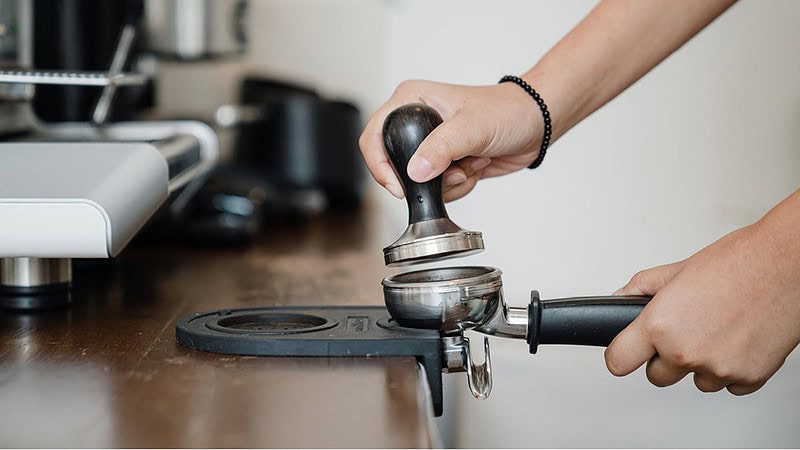 Man sieht eine Hand die den Siebträger mit Kaffeepulver befüllt- Barista Kurs mit eigener Maschine und Mühle