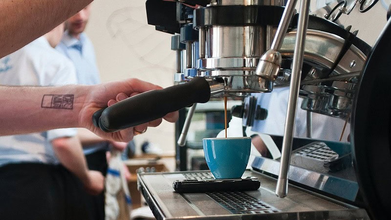 Man sieht eine Siebträgermaschine die eine Tasse Kaffee befüllt- Barista Professional Schulung in Dresden