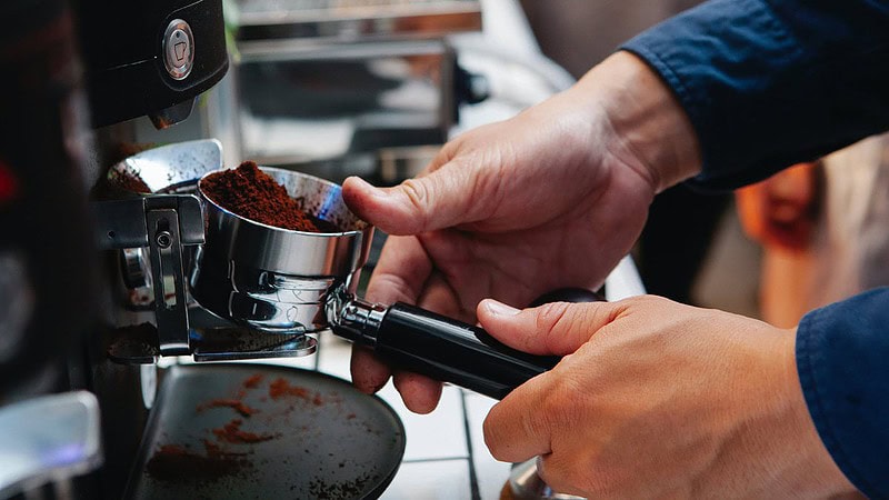 Man sieht eine elektrische Kaffeemühle, die einen Siebträger mit Kaffeepulver füllt- Barista Professional Schulung in Dresden