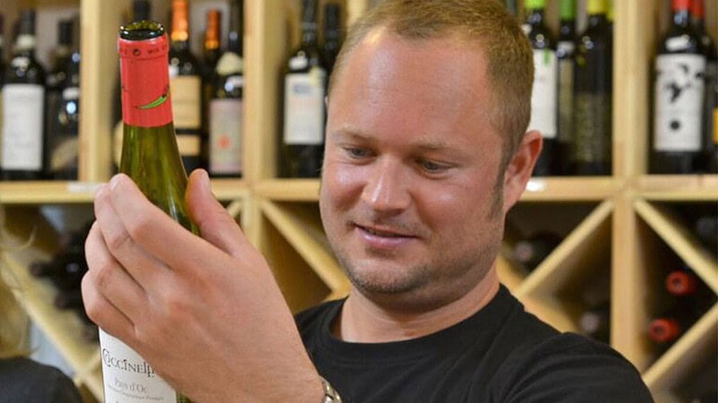 Person schaut in einem Weingeschäft den Wein an - Weinverkostung in Berlin