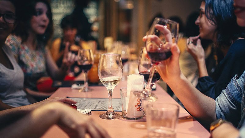 Tisch mit Menschen die beim Speed Dating Wein trinken