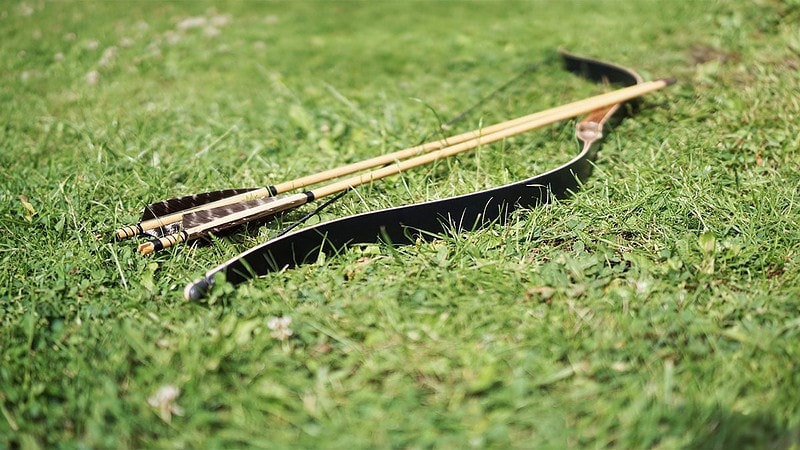 Ein Bogen mit Pfeilen liegt auf dem Gras.