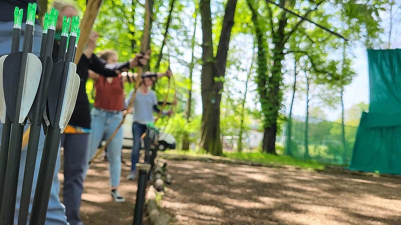 Pfeile im Köcher, im HIntergrung Bogenschießende Personen.