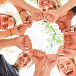 Gruppe im Kreis mit Händen in der Mitte