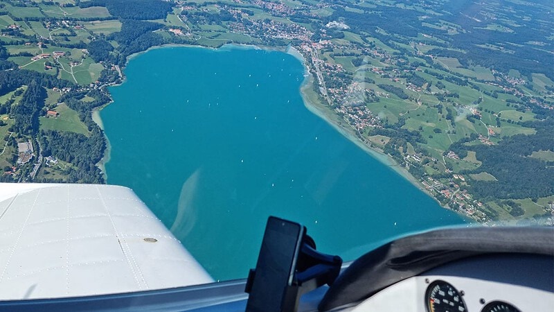 Blick aus einem Sportflugzeug auf einen See.