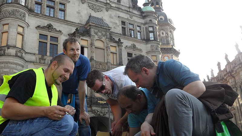 5 Männer schauen auf etwas beim Dresdner Schatzrundgang - Geocaching in historischem Ambiente