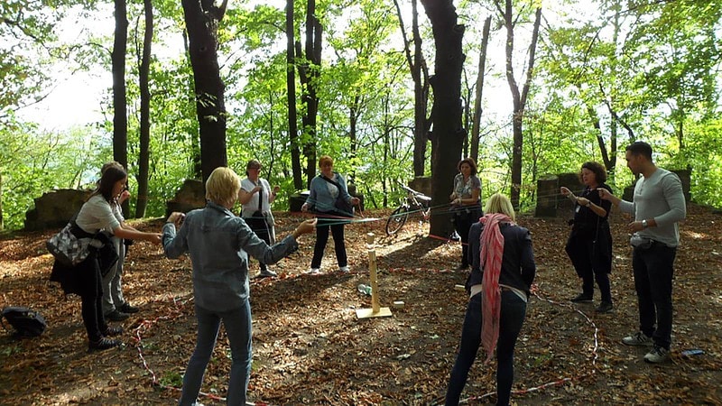 Gruppe baut einen Fröbelturm am Strick bei der Team Challenge Schnitzeljagd im Grünen