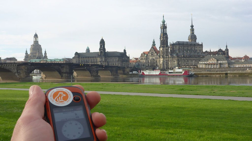 Mann hält Kompass am Dresden Elbufer bei der Team Challenge Schnitzeljagd