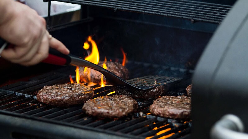 Eine Person grillt Burger Patties auf einem Grill