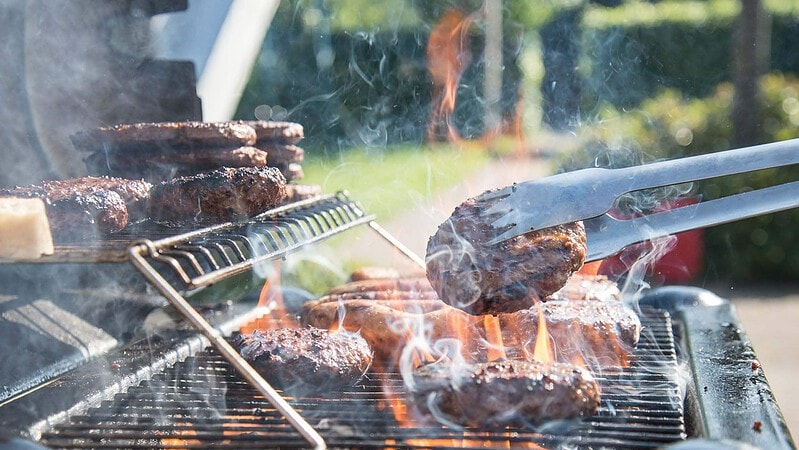 Eine Person grillt Burger Patties auf einem Grill