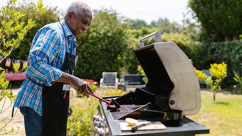 Ein lustiger Mann grillt auf einem Grill