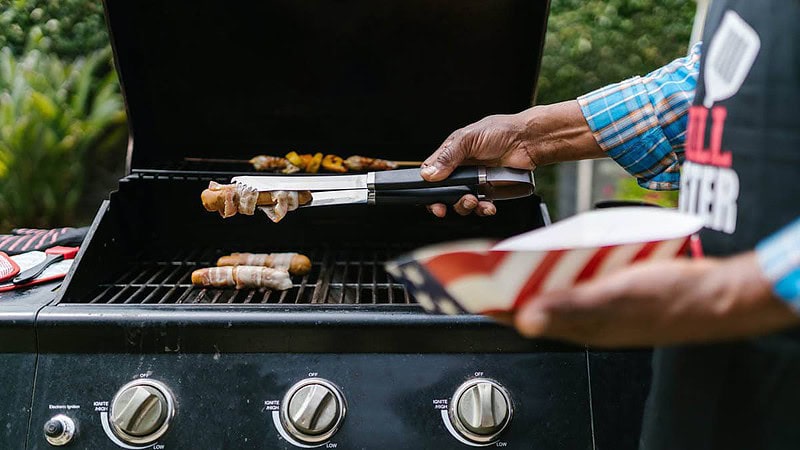 Ein Mann grillt Fleisch auf einem Gasgrill