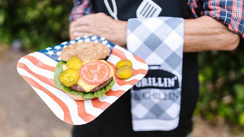 Man hält einen Teller mit einem amerikanischen Burger