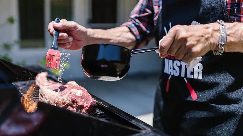 Ein Mann grillt Fleisch auf einem Gasgrill