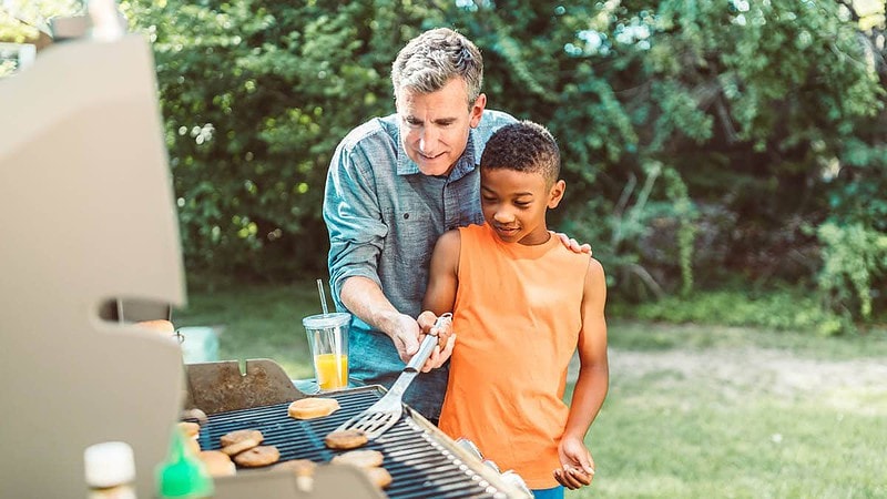 Ein Mann grillt mit einem Junge auf einem Gasgrill