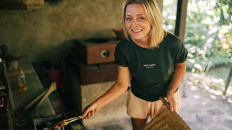 Eine blonde Frau lächelt und grillt das Essen