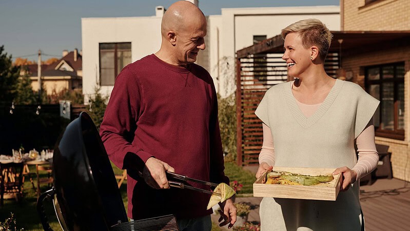 Ein Mann und eine Frau lachen und grillen Gemüse zusammen