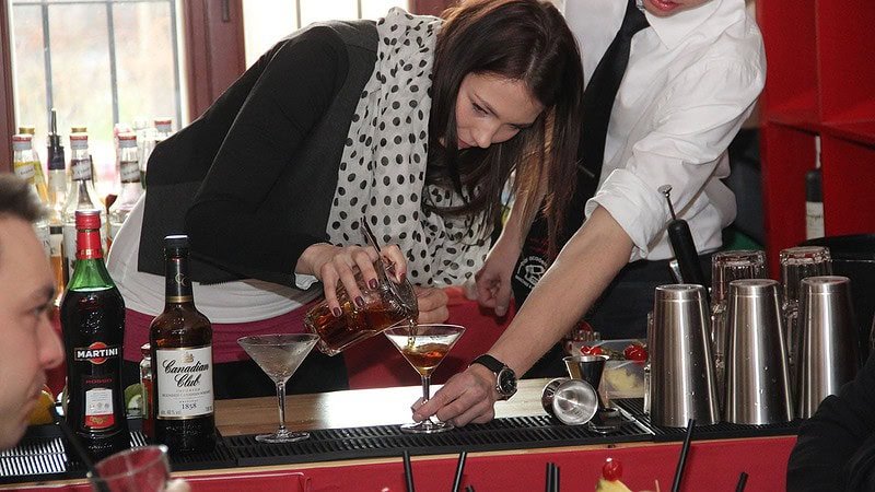 Frau gießt Cocktail aus dem Shaker ins Glas beim Cocktail Aufbaukurs in Dresden