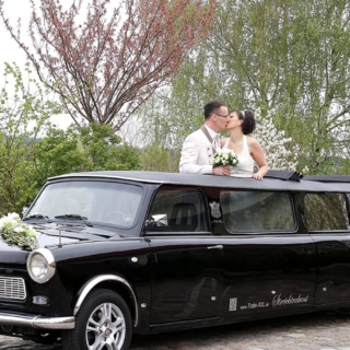 Brautpaar schaut aus dem Verdeck der Hochzeitstrabant Stretchlimousine und küsst sich