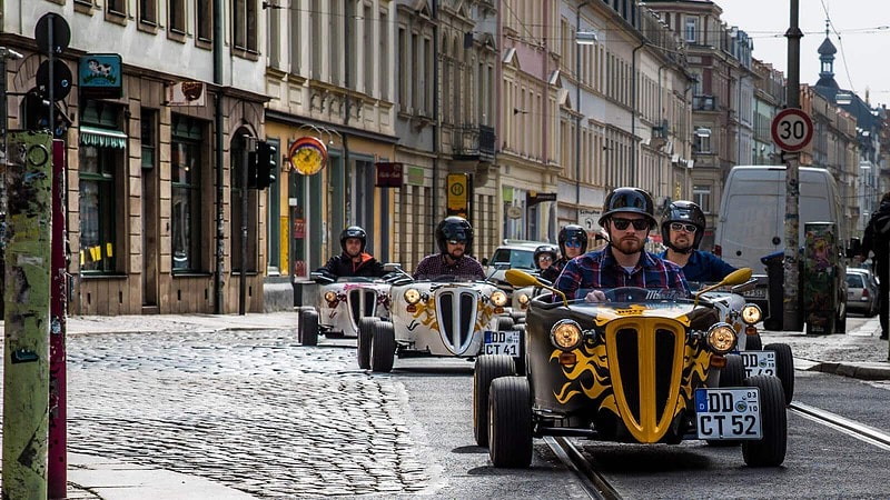 Eine Gruppe von Personen fährt mit den HotRods durch die Stadt