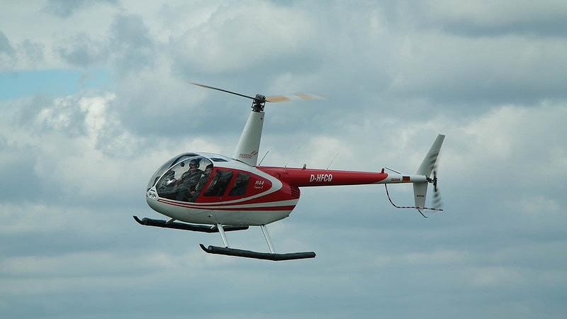 Roter Hubschrauber, fliegt, weiße Wolken, blauer Himmel