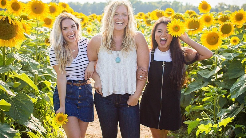 3 Frauen posieren für ein Fotoshooting in einem Sonnenblumenfeld