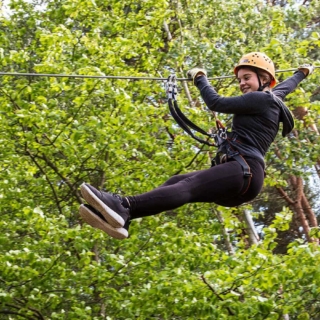 Mädchen rutscht im Kletterwald am Seil hinunter