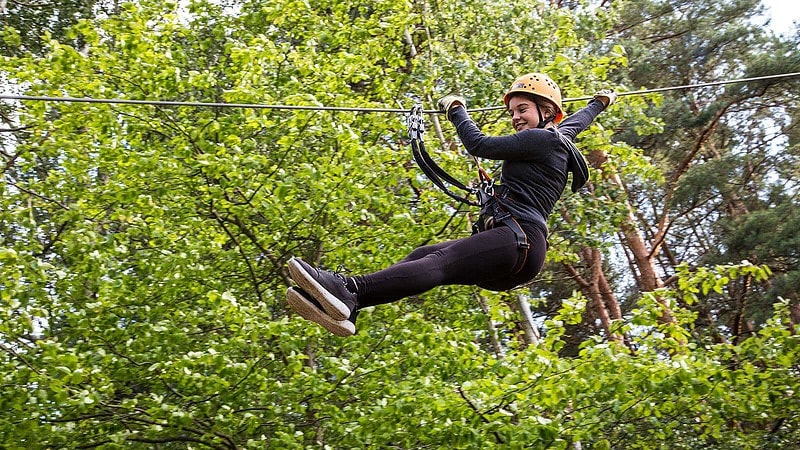 Mädchen rutscht im Kletterwald am Seil hinunter