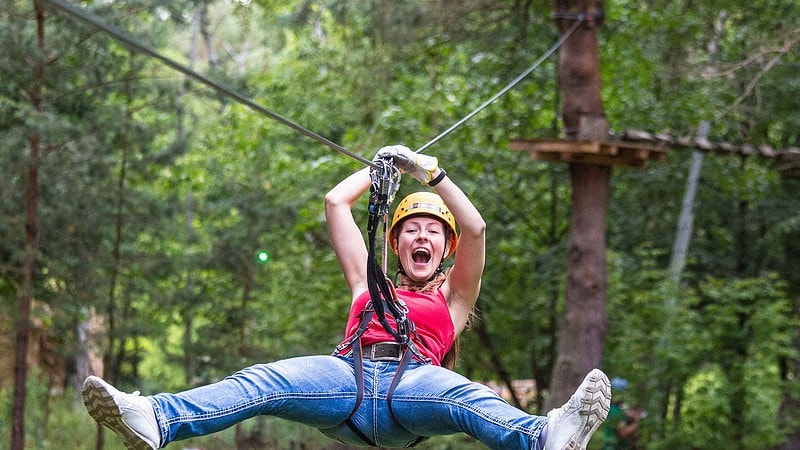 Frau hängt an der Seilrutsche im Abenteuer Kletterwald bei Potsdam