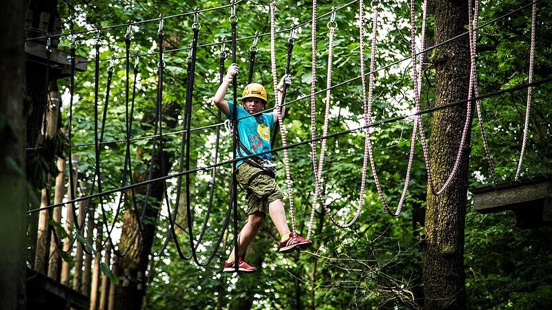 Kind steht in Kletterseilen im Abenteuer Kletterwald bei Potsdam