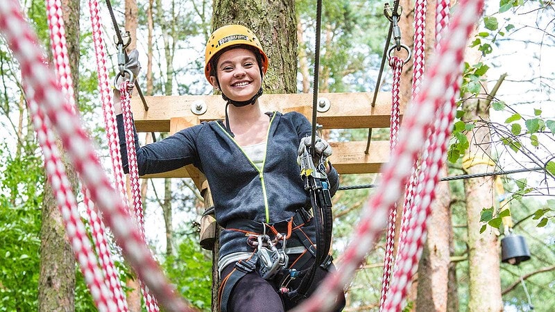 Frau mit Kletterausrüstung im Abenteuer Kletterwald bei Potsdam