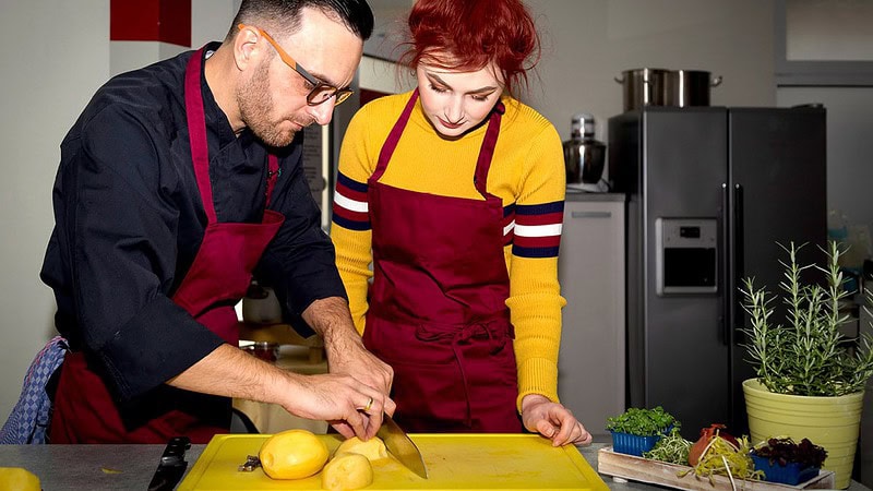 Mann zeigt Frau Schneidetechnik beim Kochkurs in Dresden