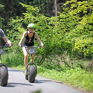 Frau und Mann auf einem Waldweg aug dem Monsterroller unterwegs