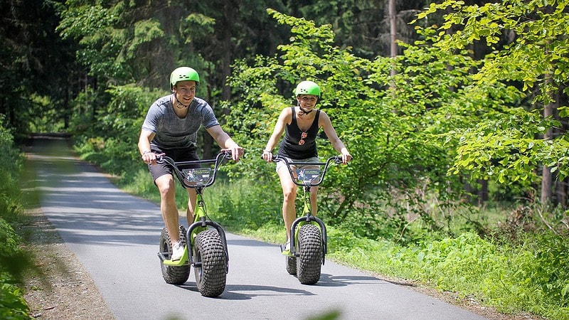 Frau und Mann auf einem Waldweg aug dem Monsterroller unterwegs