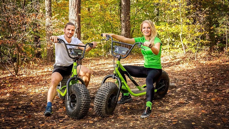 Zwei Monsterroller stehen auf im Wald mit sitzendem Mann und Frau