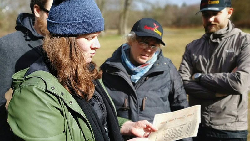 Vier Leute mit Rätselkarte in der Hand.