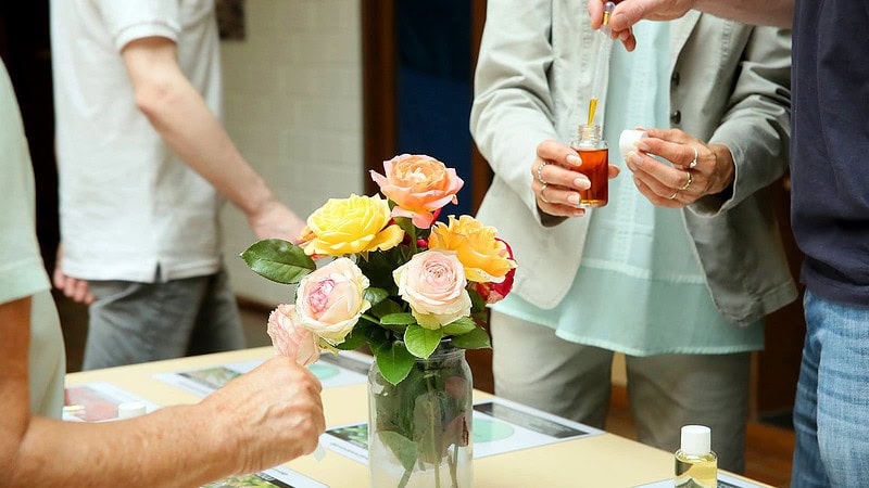 mehrere Menschen mixen einen Duft mit Rosenblättern beim Parfum Workshop