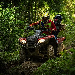 Ein Fahrer mit Beifahrer fahren auf einem Quad durch den Wald