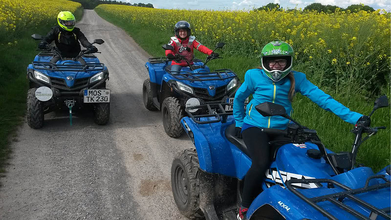 Drei Quadfahrer genießen auf den Quads die Natur.