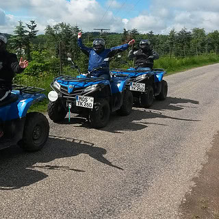 Drei Quadfahrer freuen sich mit in die Luft gestreckten Armen auf den Quads.