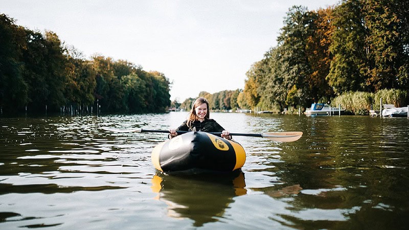 Schlauchboot mieten - Packraft auf dem Wasser mit Frau, die in die Kamera schaut und lächelt