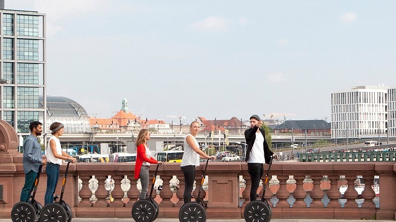 Fünf Menschen fahren über eine Brücke mit Segways