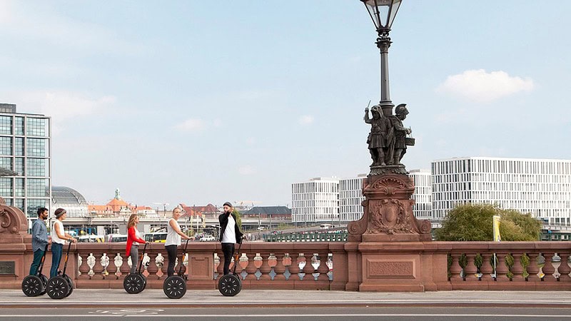 Fünf Menschen fahren mit Segways über eine Brücke