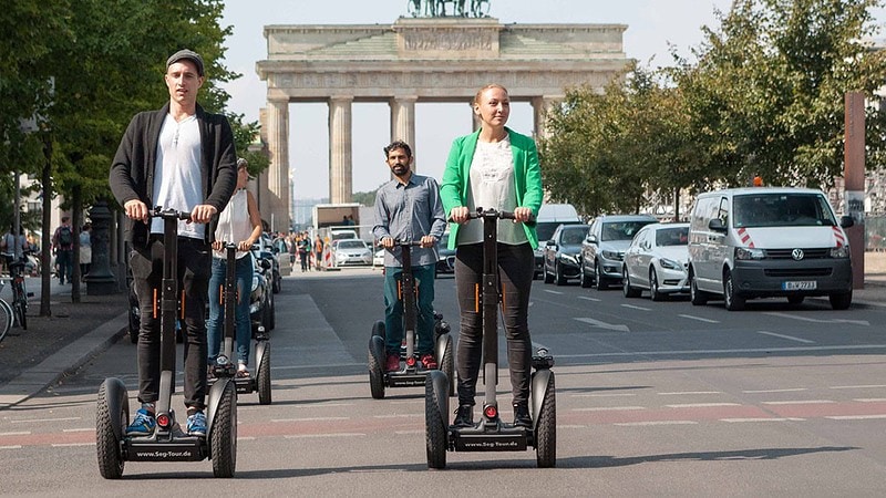 vier Menschen fahren Segway vor dem Brandenburger Tor in Berlin