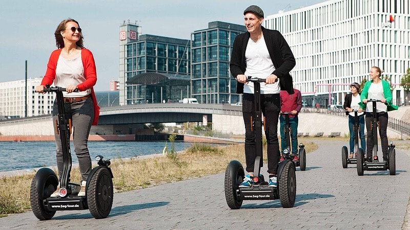 fünf Menschen fahren Segways an der Spree