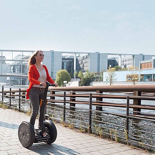 zwei Menschen fahren Segway auf einem Fußweg