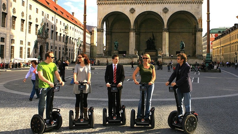 Fünf Menschen stehen auf ihren Segways auf einem großen Platz